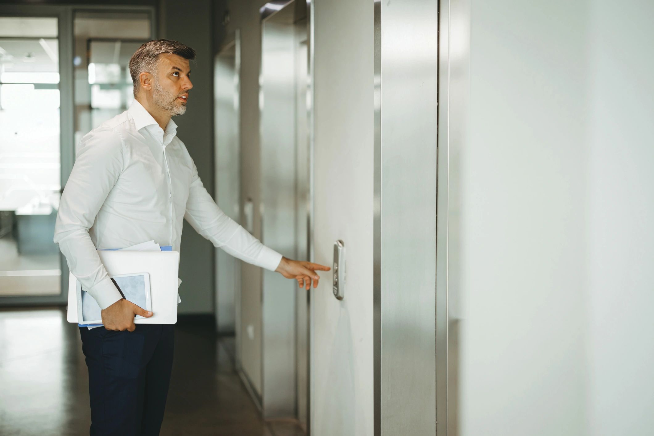 Person pressing elevator call button in office