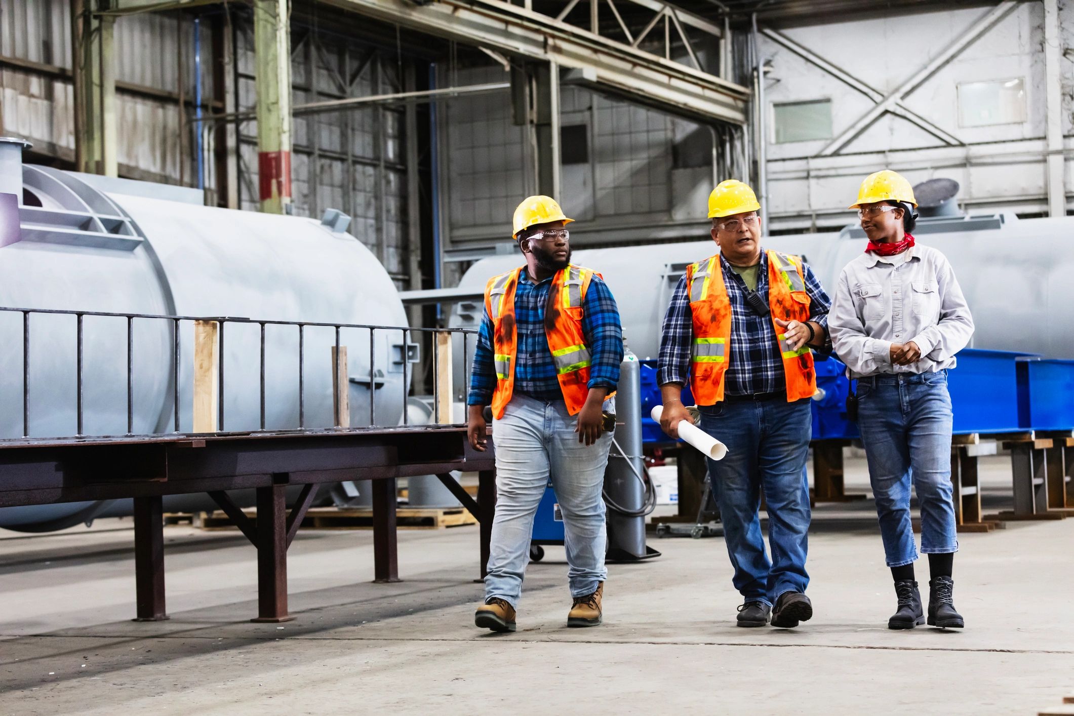 A team of industrial technicians walking through a fabrication facility